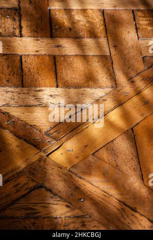 Alter Parkettboden im Morgenlicht. Spiel von Licht und Schatten. Stockfoto