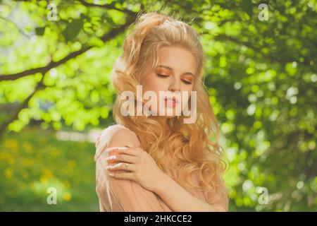 Porträt einer schönen jungen Frau, die im Sonnenlicht in der Natur im Park steht Stockfoto