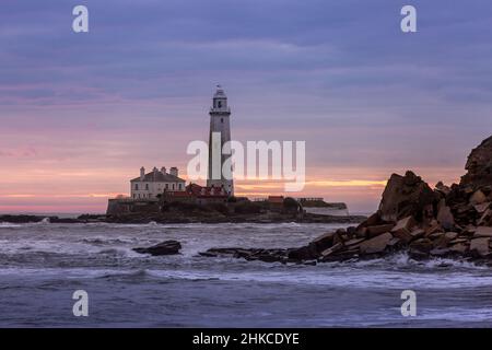 Ein spektakulärer Sonnenaufgang am St Mary's Lighthouse in Whitley Bay, wenn der Himmel in Farbe ausbricht Stockfoto