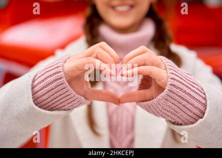 Valentinstag-Konzept. Liebe in der Luft. Frau lächelt und hält ihre Hände in Form von Herzen für Dankbarkeit. Stockfoto