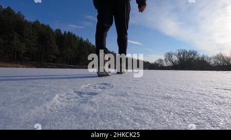 Ein Mann geht auf dem Schnee auf dem See vorwärts. Schuhe aus nächster Nähe Stockfoto