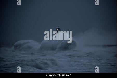 Die Sturmwinde des Sturms Arwen verursachen riesige Wellen, die den Leuchtturm und den Nordpier, die die Mündung des Tyne in Tynemouth, England, bewachen, schlagen Stockfoto