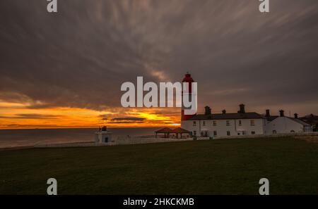 Der rot-weiß gestreifte, 23 Meter hohe Souter Lighthouse und die Leas in Marsden, South Shields, England, wenn die Sonne aufgeht Stockfoto