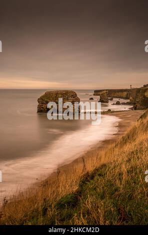 Der Blick entlang der Marshden Bay bei Sunderland, auf die Klippen und das Sandsteinmeer, wenn die Flut eintrifft Stockfoto