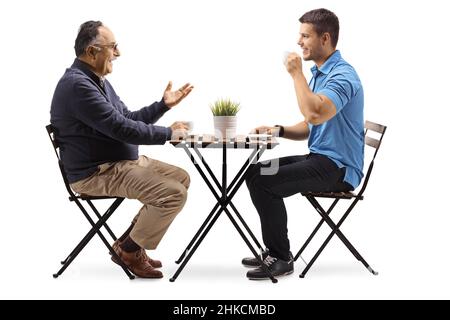 Junger und reifer Mann sitzt an einem Tisch und hat einen Kaffee isoliert auf weißem Hintergrund Stockfoto