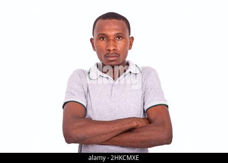 Hübscher, ernsthafter Erwachsener, der seine Arme kreuzt und vor dem Hintergrund steht. Stockfoto