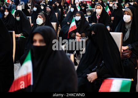 Teheran, Iran. 01st. Februar 2022. Eine verschleierte Frau, die eine Schutzmaske trägt, hält eine iranische Flagge, während sie am 1. Februar vor dem Grab des verstorbenen iranischen Führers Ayatollah Ruhollah Khomeini am ersten Tag des Sieges des Jahrestages der Islamischen Revolution auf dem Friedhof Behesht-e Zahra im Süden Teherans, Iran, sitzt. 2022. (Foto: Sobhan Farajvan/Pacific Press/Sipa USA) Quelle: SIPA USA/Alamy Live News Stockfoto