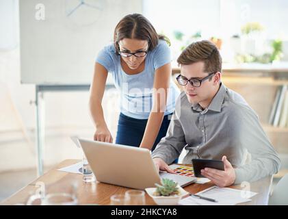 Eingetaucht in den Designprozess. Aufnahme von zwei Designern, die in einem Büro an einem Laptop arbeiten. Stockfoto