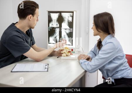 Junge Frau in Absprache mit einem Physiotherapeuten in der Arztpraxis Stockfoto