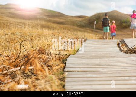 Holzweg in den Bergen. Holzfußboden. Kurvenreicher Wanderweg aus Brettern in den Bergen. Erwachsene und Kinder wandern in den Bergen entlang Stockfoto