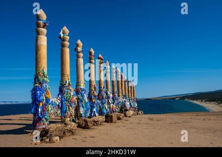 Bunte Bänder auf den Holzsäulen in der heiligen burjat Platz auf Kap Burkhan in Khuzhir Dorf in Olchon Insel, Baikalsee, Russland Stockfoto