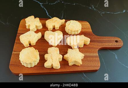 Frisch gebackene hausgemachte Kekse auf Holzbrett isoliert auf schwarzem Hintergrund Stockfoto