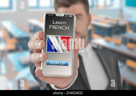 Online-Konzept Französisch lernen mit einer Person zeigen E-Learning-App auf dem Handy mit der Flagge von Frankreich Stockfoto