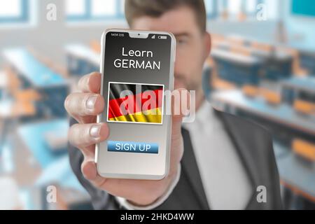 Online-Konzept Lernen Sie die deutsche Sprache mit einer Person, die die E-Learning-App auf dem Mobiltelefon mit der Flagge Deutschlands zeigt Stockfoto
