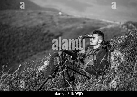 Jäger mit Jagdgewehr und Jagdform zur Jagd. Hunter zielt. Shooter Sichtung in das Ziel. Der Mann ist auf der Jagd. Jagdgewehr jagen. Jäger Stockfoto