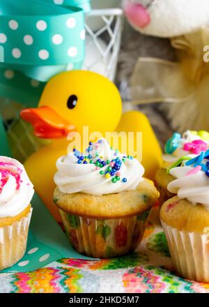 Eine Nahaufnahme von verschiedenen Mini-Cupcakes mit Osterkorb im Hintergrund. Stockfoto