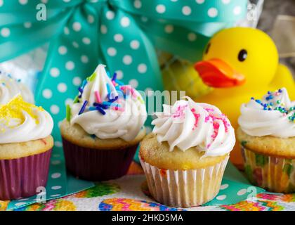 Eine Nahaufnahme von verschiedenen Mini-Cupcakes mit Osterkorb im Hintergrund. Stockfoto