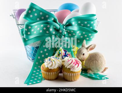 Verschiedene Mini-Cupcakes mit Osterkorb im Hintergrund. Stockfoto