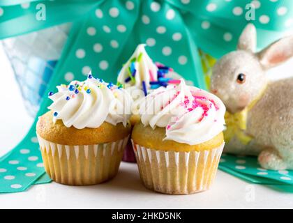 Eine Nahaufnahme von verschiedenen Mini-Cupcakes mit Osterkorb im Hintergrund. Stockfoto