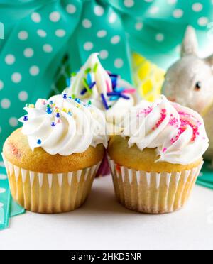 Eine Nahaufnahme von verschiedenen Mini-Cupcakes mit Osterkorb im Hintergrund. Stockfoto