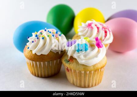 Verschiedene Mini-Cupcakes mit Ostereiern im Hintergrund verschwommen. Weißer Hintergrund. Stockfoto