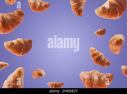 Frisch gebackene Croissants schweben oder fliegen. Ein Satz Croissants fliegt in der Luft isoliert auf sehr pery purpurem Hintergrund. Speicherplatz kopieren. Schildermockup, Werbung für Bäckerei. Kreatives Frühstück Stockfoto