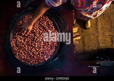 Eine indigene Amuzgo-Frau röstet Kakaobohnen auf einem Tonteller über Feuer in der handwerklichen Schokoladenherstellung in Xochistlahuaca, Guerrero, Mexiko. Stockfoto