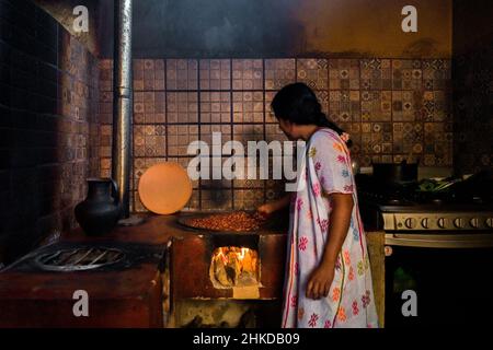 Eine indigene Frau aus Amuzgo röstet Kakaobohnen auf einem Tonteller über Feuer in der handwerklichen Schokoladenherstellung in Xochistlahuaca, Mexiko. Stockfoto