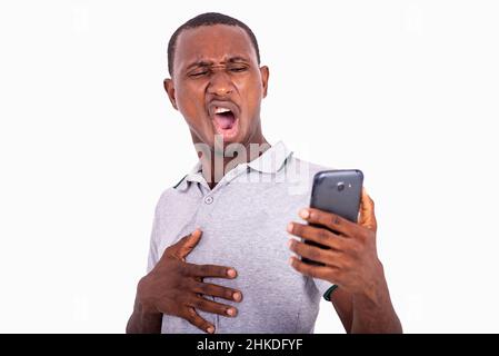 Junger Mann, der auf das Mobiltelefon schaut, schockiert, Mund weit geöffnet. Stockfoto