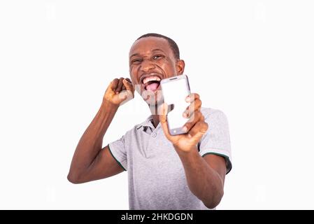 Junger glücklicher Mann mit offenem Mund, der hält und den Bildschirm des Mobiltelefons zeigt. Stockfoto