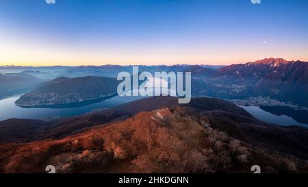 Blick auf die kleine Kirche auf dem Gipfel des Monte San Giorgio, die den Luganersee dominiert. Monte San Giorgio, Brusino Arsizio, Kanton Tessin, Schweiz. Stockfoto