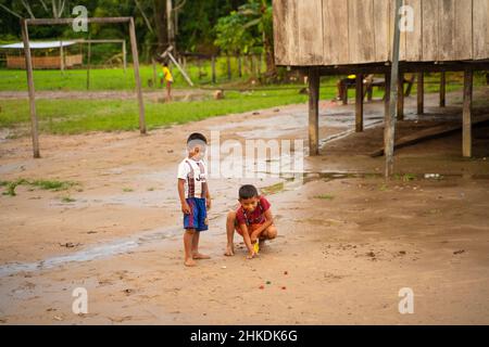 In der indigenen Gemeinde Gamboa, Amazonien, Peru, 1. Januar 2022. Kinder spielen mit Flaschenverschlüssen Stockfoto