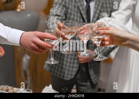 Die Menschen feiern und heben Gläser Wein zum Anstoßen. Gäste mit Champagner bei der Hochzeit. Stockfoto