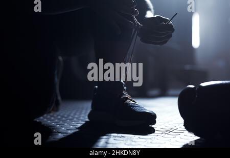 Noch mehr Spielspaß. Nahaufnahme eines nicht erkennbaren Mannes, der seine Schnürsenkel in einem Fitnessstudio bindet. Stockfoto