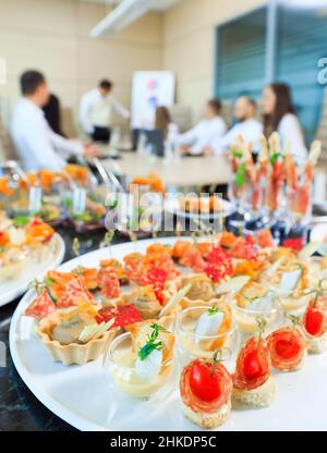 Catering im Büro. Ein Tisch mit Häppchen und verschiedenen Snacks wird im Rahmen eines Geschäftstreffens serviert Stockfoto