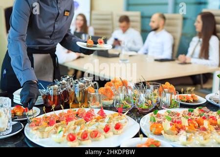 Der Kellner legt Essen für die Verpflegung aus Stockfoto