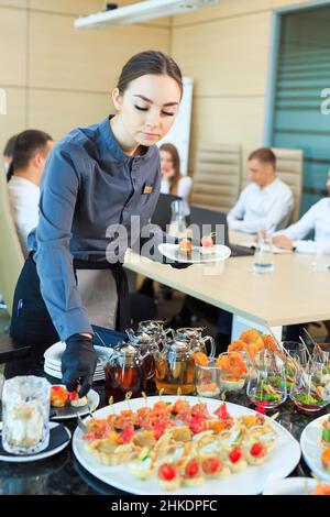 Der Kellner legt Essen für die Verpflegung aus Stockfoto