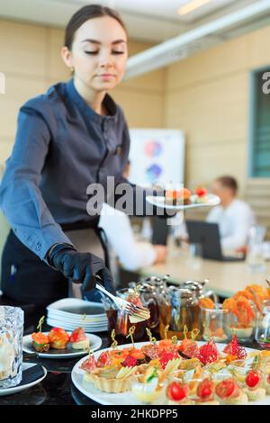 Der Kellner legt Essen für die Verpflegung aus Stockfoto