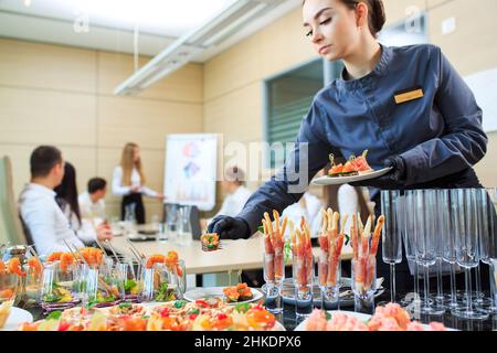 Der Kellner legt Essen für die Verpflegung aus Stockfoto