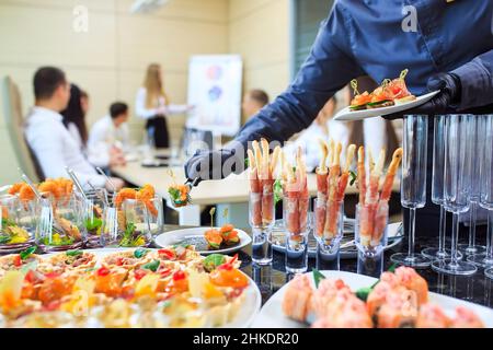 Der Kellner legt Essen für die Verpflegung aus Stockfoto