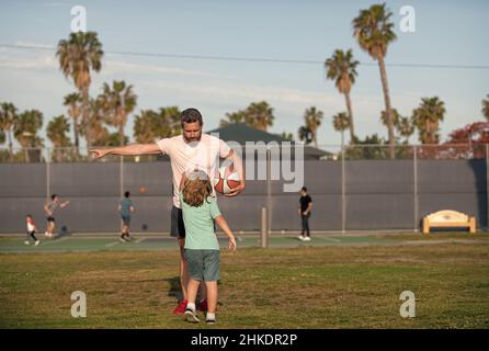 Junge Kind hören Mann Trainer erklären Basketballregeln auf Sportplatz, Sporttraining Stockfoto