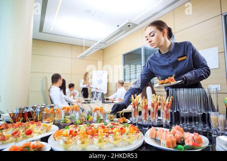 Der Kellner legt Essen für die Verpflegung aus Stockfoto