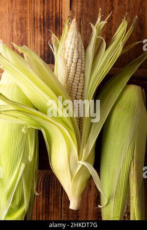 Nahaufnahme des rohen weißen Mais auf der Kohle auf rustikaler Holzoberfläche. Stockfoto