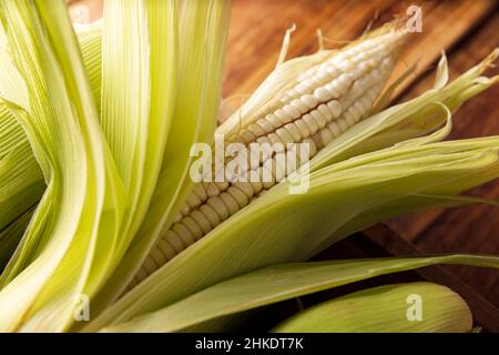 Nahaufnahme des rohen weißen Mais auf der Kohle auf rustikaler Holzoberfläche. Stockfoto