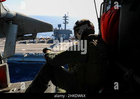 SÜDCHINESISCHES MEER (FEB 1, 2022) Senior Chief Naval Aircrewman (Hubschrauber) Justin Wright aus Linden, Kalifornien, beobachtet den Flugzeugträger USS Abraham Lincoln (CVN 72) der Nimitz-Klasse aus der Kabine eines Hubschraubers MH-60s Sea Hawk, der den 'Chargers' des Helicopter Sea Combat Squadron (HSC) 14 zugewiesen wurde. Die Abraham Lincoln Strike Group befindet sich im geplanten Einsatzgebiet der US-Flotte für 7th, um die Interoperabilität durch Allianzen und Partnerschaften zu verbessern und gleichzeitig als reaktionsfähige Truppe zur Unterstützung einer freien und offenen Region im Indo-Pazifik-Raum zu dienen. (USA Navy Foto von Mass Communication Specia Stockfoto