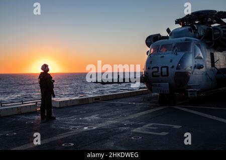 220201-N-PC065-1049 ATLANTIK – Lanze CPL. Brandon Pope, der Marine Medium Tiltrotor Squadron (VMM) 263 (verstärkt) zugewiesen wurde, kommuniziert während des Flugbetriebs an Bord des amphibischen Transportschiffes USS Arlington (LPD 24) der San Antonio-Klasse mit Piloten in einem CH-53E Super Henglion Hubschrauber, 1. Februar 2022. Die Kearsarge Amphibious Ready Group (ARG) und die 22nd Marine Expeditionary Unit (MEU) führen derzeit eine Composit Training Unit Exercise (COMPTUEX) durch. COMPTUEX ist die letzte Vorbereitungs-Übung, die die Fähigkeit der Kearsarge ARG und 22nd MEU zur Durchführung militärischer Maßnahmen bescheinigt Stockfoto