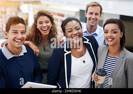 Zusammenkommen für den Erfolg des Teams. Porträt einer Gruppe lächelnder Mitarbeiter, die in einem Büro stehen. Stockfoto