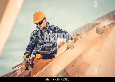 Holzhaus Dach Skelett Frame Assembly von professionellen Bauarbeiter. Kaukasischer Auftragnehmer Mit Gelbem Harthut. Stockfoto