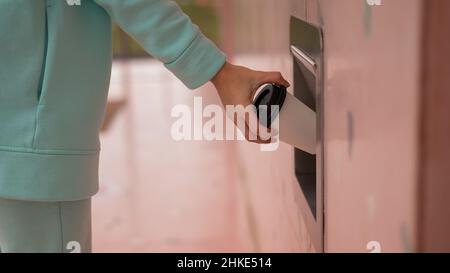 Eine Frau wirft eine Tasse Kaffee in einen Mülltonnen in der Wand eines Cafés. Stockfoto