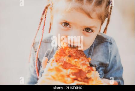 Kinder essen Pizza. Fastfood für Kinder. Junkfood-sucht. Italienische Küche. Kinderessen. Adipositas im Kindesalter. Leckeres Essen für Kinder. Stockfoto